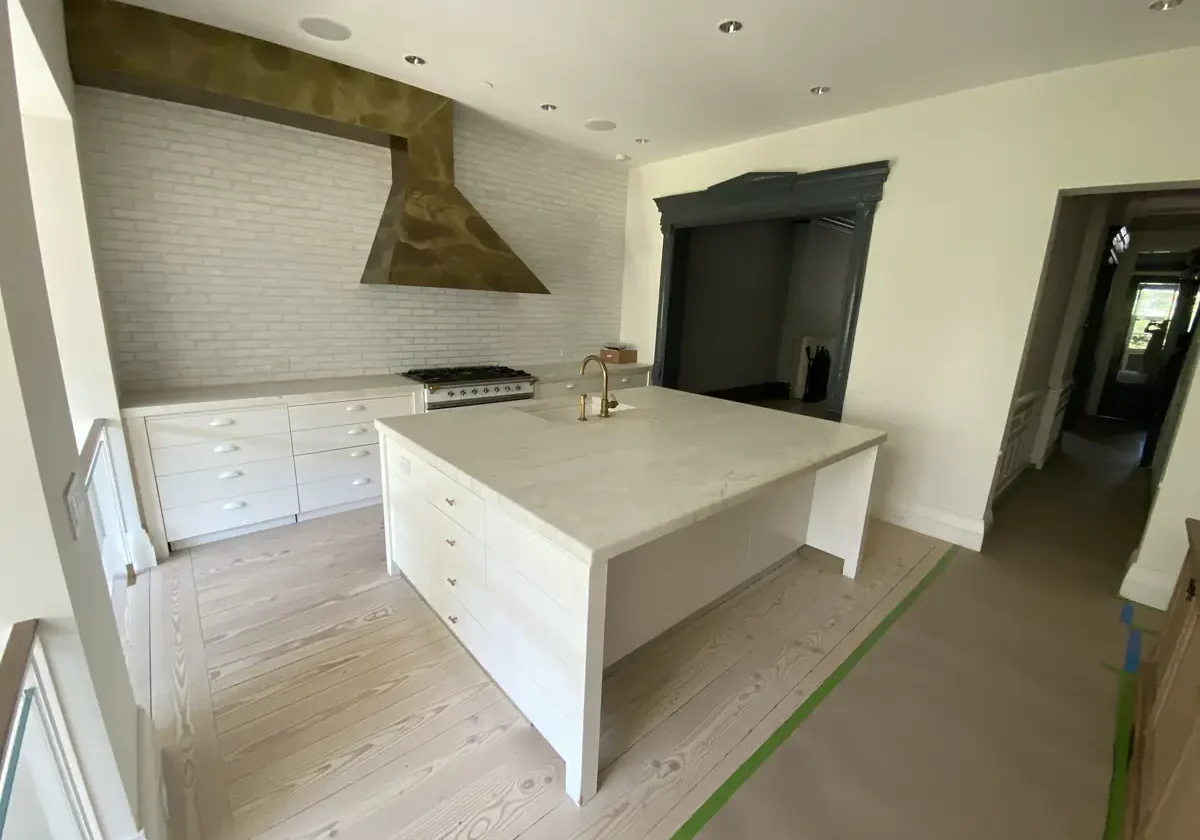 Kitchen remodel with large white island and custom range hood